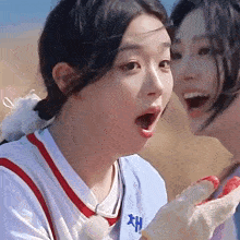 a girl wearing a white shirt with the letter h on it looks surprised