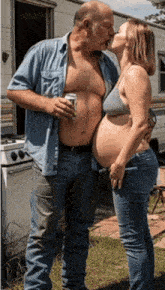 a shirtless man kisses a pregnant woman on the cheek