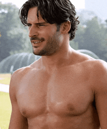 a shirtless man with a beard is smiling and looking away from the camera