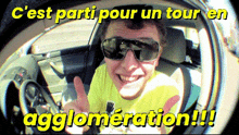 a man wearing sunglasses is sitting in a car with the words c'est parti pour un tour en agglomeration