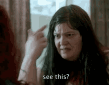 a woman is pointing at herself in the mirror and says `` see this ? ''
