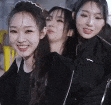 three young women are posing for a picture and one of them is wearing a nike jacket