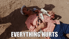 a man is laying on the ground with money around his neck and the words everything hurts written below him