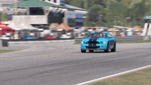 a blue car with a black stripe on the side is driving down a race track