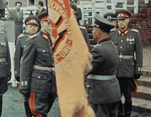 a group of men in military uniforms stand in front of a flag that says " und "