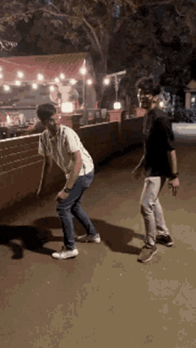 two young men are dancing on a sidewalk in front of a restaurant