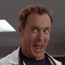 a man in a lab coat is smiling with his eyes closed and his mouth open .
