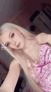 a woman with long blonde hair is taking a selfie in a pink hello kitty outfit