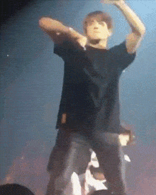 a man in a black shirt is dancing on a stage with his arms outstretched
