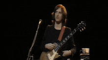 a man is singing into a microphone while playing a guitar on stage .