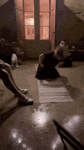 a man is kneeling down on a rug in a room with other people .