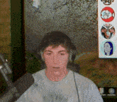 a young man wearing headphones and a white shirt is sitting in front of a microphone in front of a painting