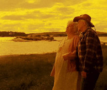 a man and a woman standing in a field looking at a body of water