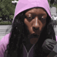 a woman wearing a pink hoodie is talking into a microphone