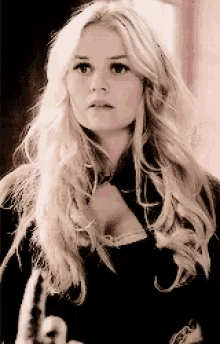 a woman with blonde hair is wearing a black top and a black coat .