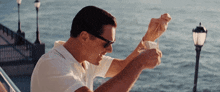 a man wearing sunglasses is holding a piece of paper in front of the ocean