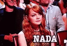 a woman with red hair is sitting in a crowd and the word nada is on the screen