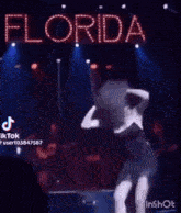 a woman in a black dress is dancing on a stage in a dark room .