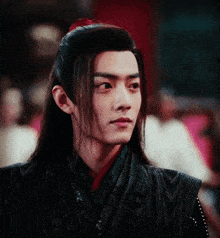 a man with long hair is wearing a black and red outfit