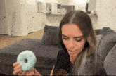 a woman sitting on a couch holding a donut with a hole in it