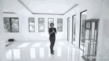 a woman stands in an empty room with a clock in front of her