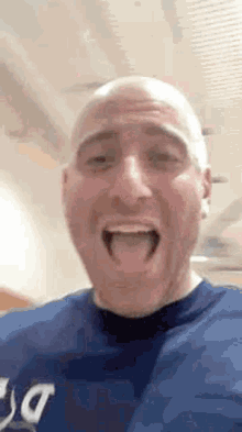 a man with a bald head is making a funny face with his tongue out .