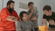 a group of men are standing around a table in front of a sign that says studios