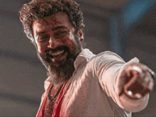 a man with a beard and blood on his face is pointing his finger at the camera .