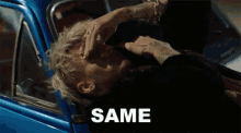 a man is laying in a blue car with the word same on the bottom