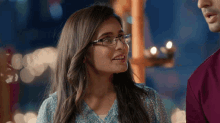 a woman wearing glasses and a blue shirt smiles