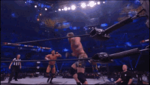 a referee stands between two wrestlers in a ring that says aew on the wall
