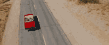 an aerial view of a red car driving down the road