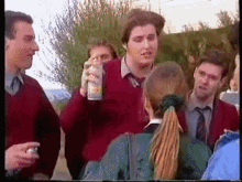 a man in a red sweater holds a can of soda in his hand