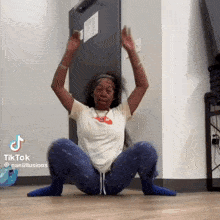 a woman is squatting on the floor with her arms in the air .