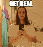 a woman is taking a selfie in front of a mirror with the words get real above her