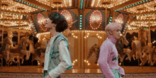 a couple of people standing in front of a merry go round .