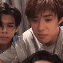 a group of young men are sitting next to each other and one of them is making a funny face .
