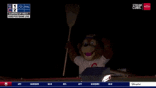 a chicago cubs mascot is holding a broom in a dark room