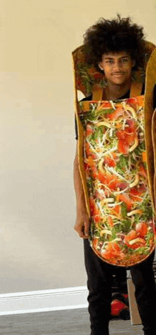 a man in a pizza costume is standing in a room holding a skateboard .