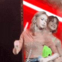two women are dancing on a stage with a red background .