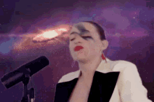 a woman in a tuxedo is singing into a microphone