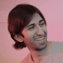 a man is smiling in front of a pink background