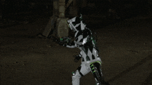 a person in a white suit with green stripes on the pants is standing in the dark