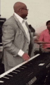 a man in a suit plays a yamaha keyboard