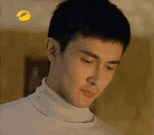 a man in a white turtleneck looks down with a yellow circle in the background