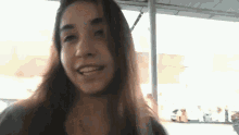 a woman with long hair is smiling and looking at the camera while standing under a canopy .