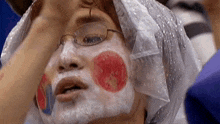 a person wearing glasses and a plastic bag on their head has a painted face