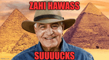 a man wearing a hat with the words " zahi hawass suuuucks " written in red