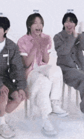 a group of young men are sitting on chairs laughing and clapping their hands .