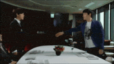 a man in a blue jacket is reaching out to another man
